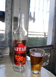 Glass of Seabuckthorn alcohol with emptied bottle.