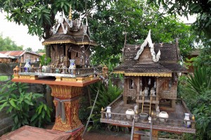 Two wooden shrines outside in someone's front yard.