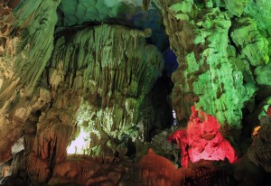 Colorfully lit rock formations inside Thien Cung Grotto.