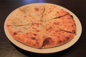 A khachapuri filled with cheese and millet.