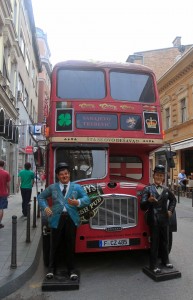 A double-decker bus and statues of Stan Laurel and Oliver Hardy outside of the "Cheers" pub in Sarajevo.