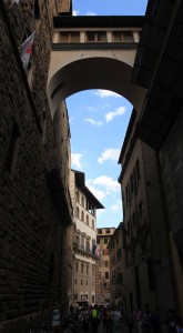 A street in Florence with a high bridge connecting two buildings.