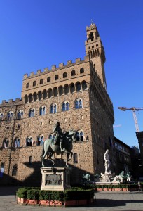 An equestrian statue in the Piazza della Signoria with the Palazzo Vecchio in the background.
