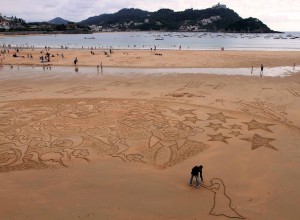A man drawing in the wet sand.