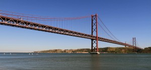 The 25 de Abril Bridge with Christ the Redeemer statue in the distance (modeled after the one in Rio de Janeiro).