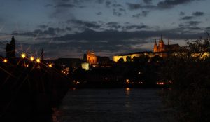 Charles Bridge, the Vltava River, and Prague Castle (with St. Vitus Cathedral) at night.